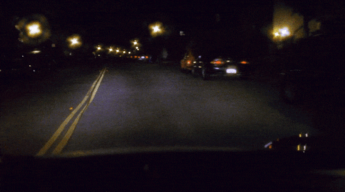 a blurred image of a street at night with a no parking sign in the background