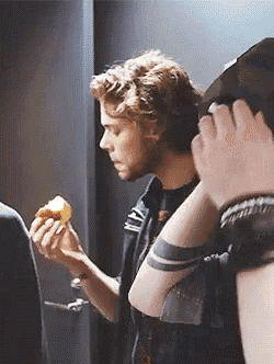 a man with a tattoo on his wrist is eating a donut