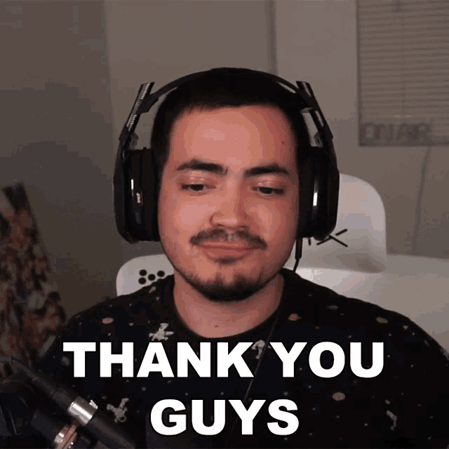 a man wearing headphones says " thank you guys " in front of a microphone