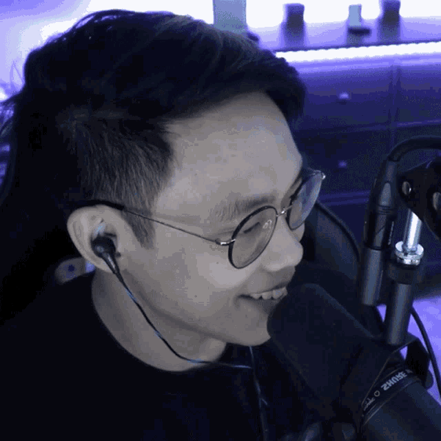 a man wearing glasses and ear buds is talking into a shure microphone