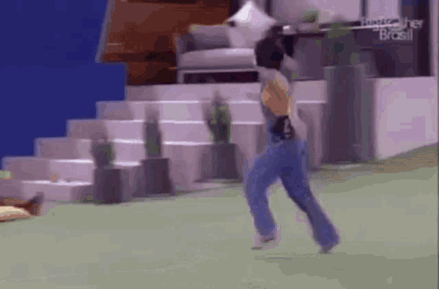 a woman in blue jeans is running on a green field