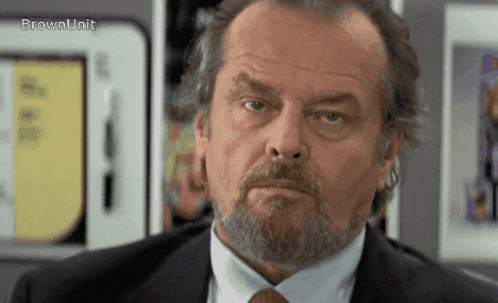 a man with a beard wearing a suit and tie is looking at the camera with the words brownunit above him