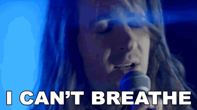 a man singing into a microphone with the words " i can 't breathe " next to him