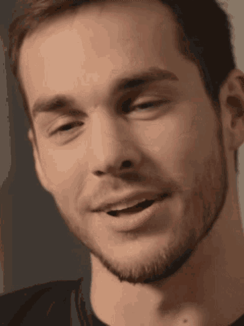 a man with a beard is smiling with his mouth open .