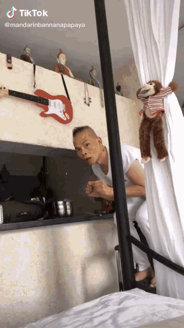 a man stands in front of a wall with a guitar and a stuffed monkey on it