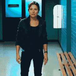 a woman standing in a hallway with a sign on the wall that says ' emergency exit '