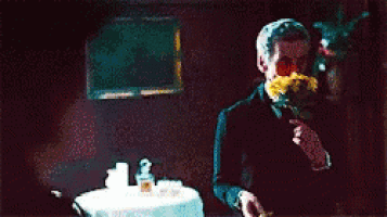 a man in a tuxedo holds a rose in his mouth