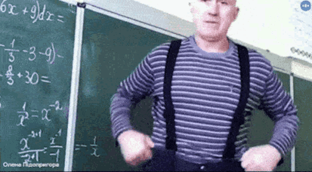 a man wearing suspenders is standing in front of a blackboard with math equations on it .