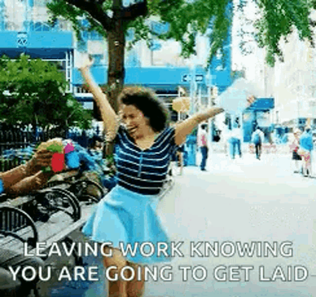 a woman is dancing in a park with her arms in the air while a man holds a cupcake .
