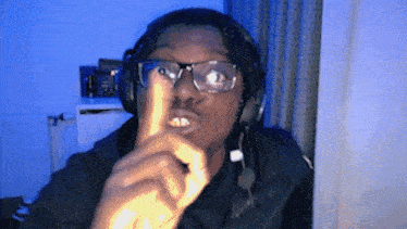 a man wearing glasses and headphones points his finger up