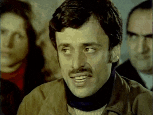 a man with a mustache is smiling and looking at something