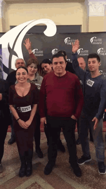 a group of people posing in front of a wall that says ' theatre ' on it