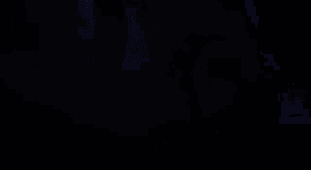 a man is flying through the air in front of a monster in a dark room .