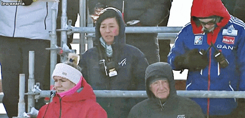 a man wearing a jacket that says gan is standing next to a woman in a red jacket