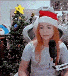 a woman wearing a santa hat is sitting in front of a microphone .