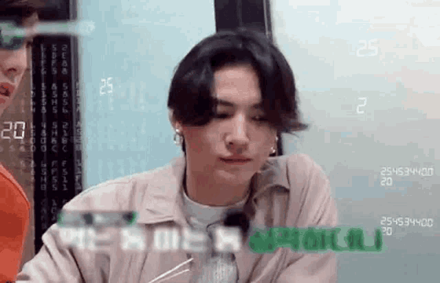 a man with long hair is sitting at a table with chopsticks in front of a computer screen .