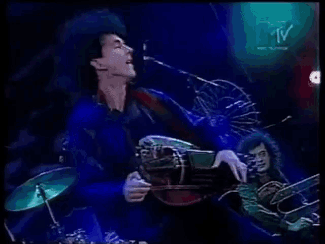 a man playing a guitar in front of a mtv logo