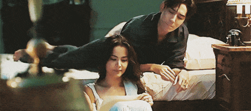 a man and a woman are laying on a bed with the man laying on the woman 's lap