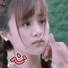 a close up of a girl 's face with her hand on her chin and a sticker on her face .
