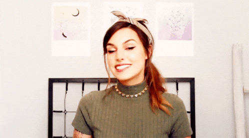 a woman wearing a turtleneck and a necklace smiles