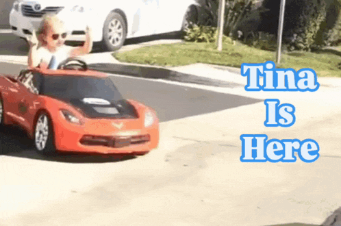 a little girl is driving a red toy car with the words tina is here