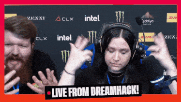 a woman wearing headphones is dancing in front of a sign that says " live from dreamhack "