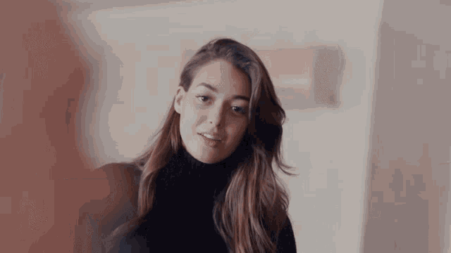 a woman is wearing a black turtleneck sweater and looking at the camera