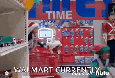 a man in a santa hat is pushing a red shopping cart in a walmart store .