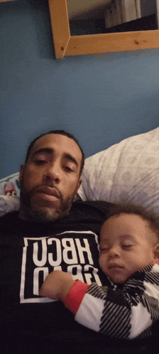 a man is holding a baby who is wearing a shirt that says " hben "