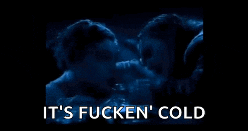 a man and woman are kissing in a dark room with the words `` it 's fucken ' cold '' written in white .