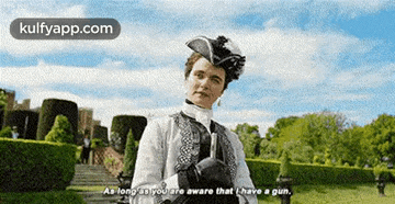 a woman in a costume is holding a gun in a park .