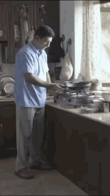 a man in a blue shirt and white pants is cooking in a kitchen