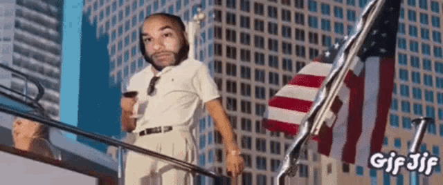 a man is standing on a balcony with an american flag in the background .