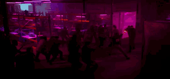 a blurry picture of people dancing in a dark room with purple lights