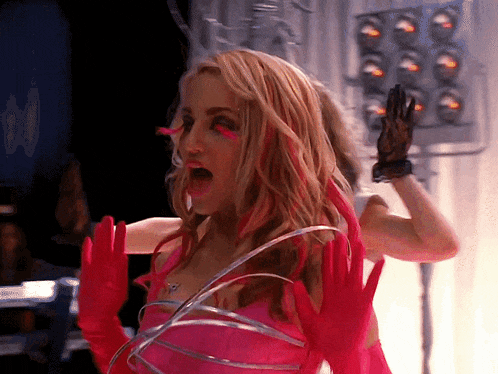 a woman wearing pink gloves and a necklace with the letter t on it