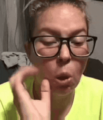 a woman wearing glasses and a neon yellow shirt is making a face .