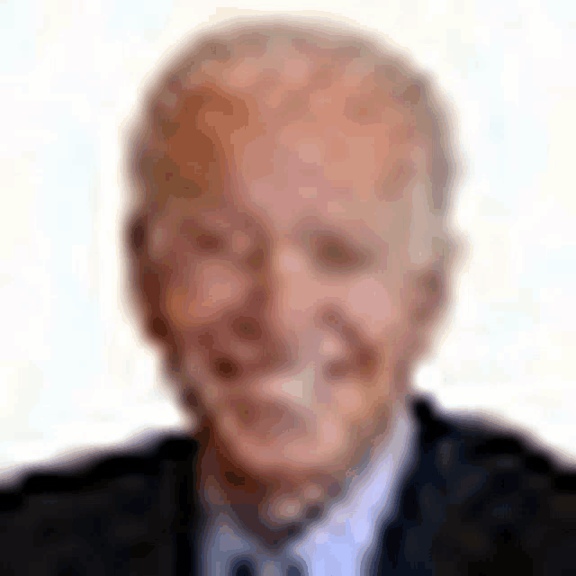 a blurry picture of a man wearing a suit and tie is smiling .
