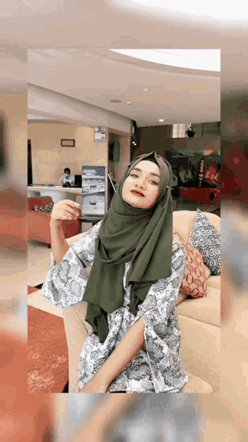 a woman wearing a hijab is sitting on a couch