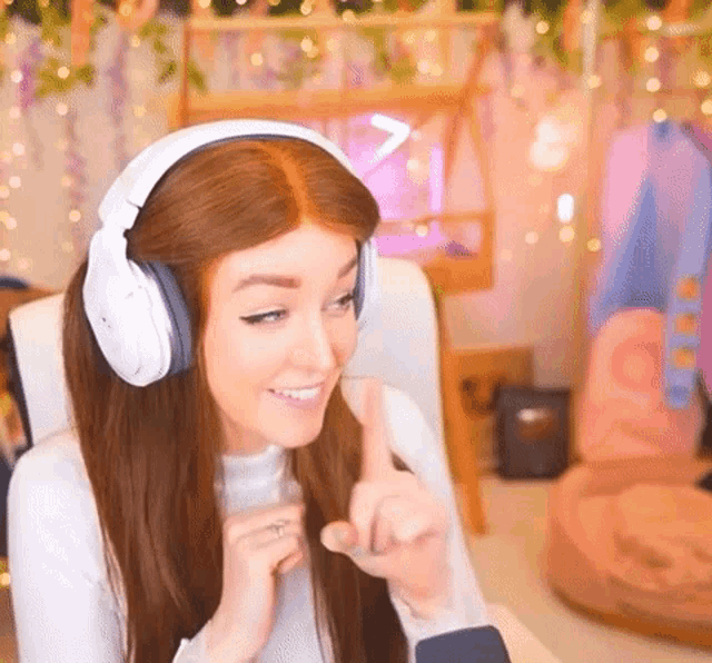 a woman wearing headphones is giving a thumbs up while sitting in a chair .