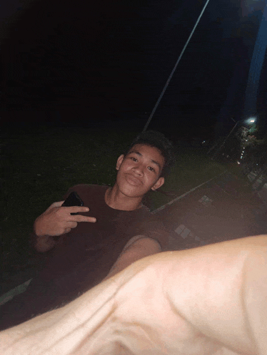 a young man giving a peace sign while holding a phone