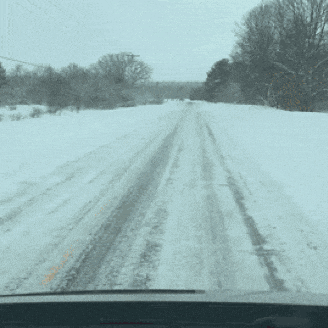a snowy road with a few trees on the side of it