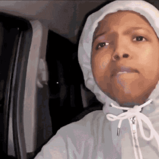 a woman wearing a hoodie is sitting in a car .