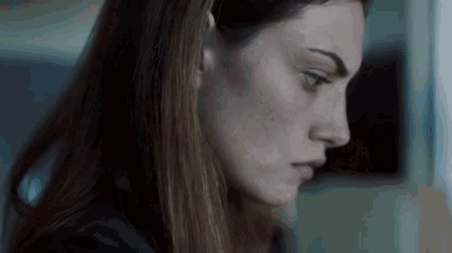 a close up of a woman 's face with long hair looking down