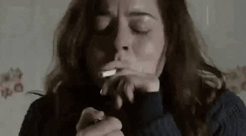 a woman is smoking a cigarette while holding a lighter .