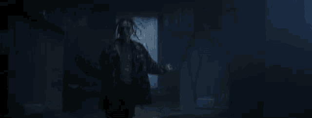 a man is standing in a dark room with his arms outstretched and a microphone in his hand .