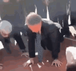 a man in a suit and tie is doing push ups .