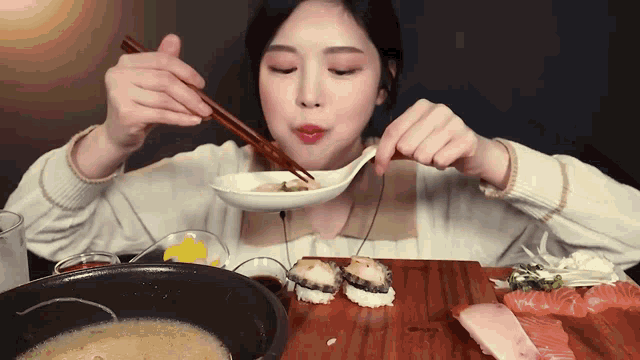 a woman is eating food with chopsticks and a spoon