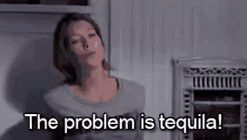 a woman is standing in front of a refrigerator with the words `` the problem is tequila '' written on it .