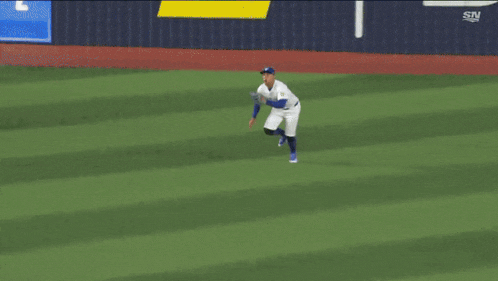 a baseball player is running on a field with a sn logo in the background .