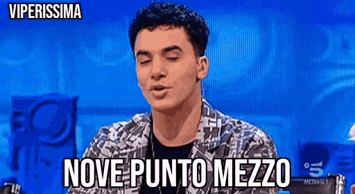 a young man is sitting in front of a screen with the words nove punto mezzo written on it .